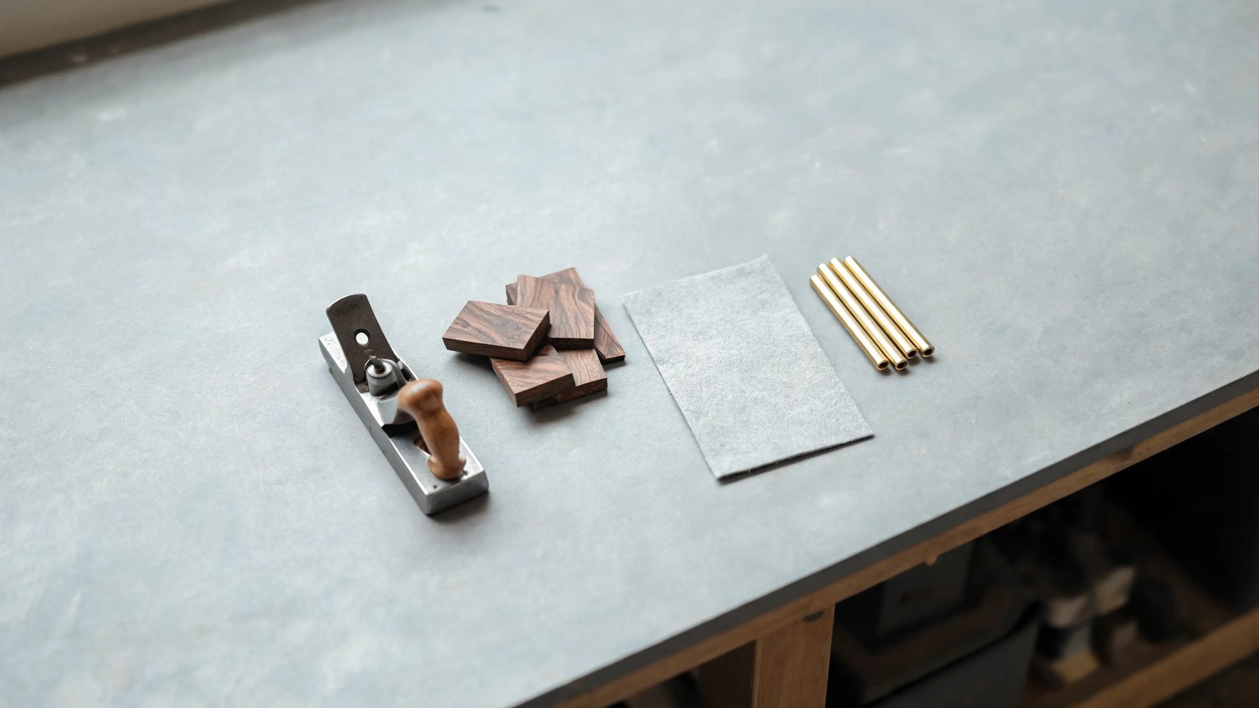 Workshop bench with a hand plane, walnut offcuts and brass rod stock